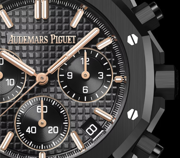 <p>ブラックの「グランデ・タペストリー」パターン文字盤に、ピンクゴールドのアップライドインデックスとロイヤルオーク針(夜光付き)を備え、視認性と質感を両立。</p>