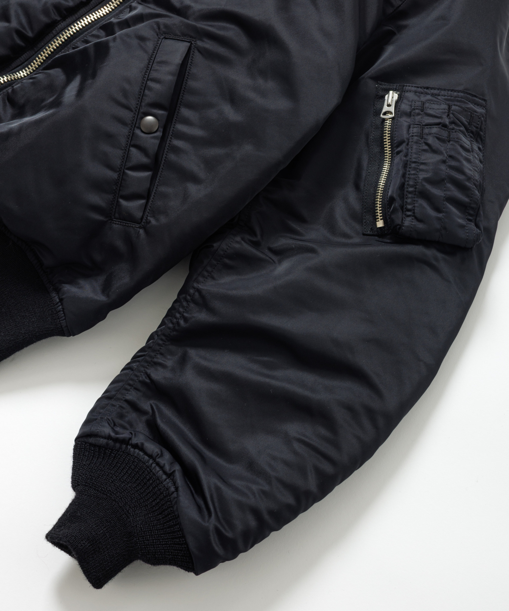 <p>生地には耐久性のある66ナイロン、中綿にはリサイクル素材とウールモッサ端材を採用。袖リブは希少織機によるウール100%チューブリブで、快適な着用感と環境への配慮を両立。</p>