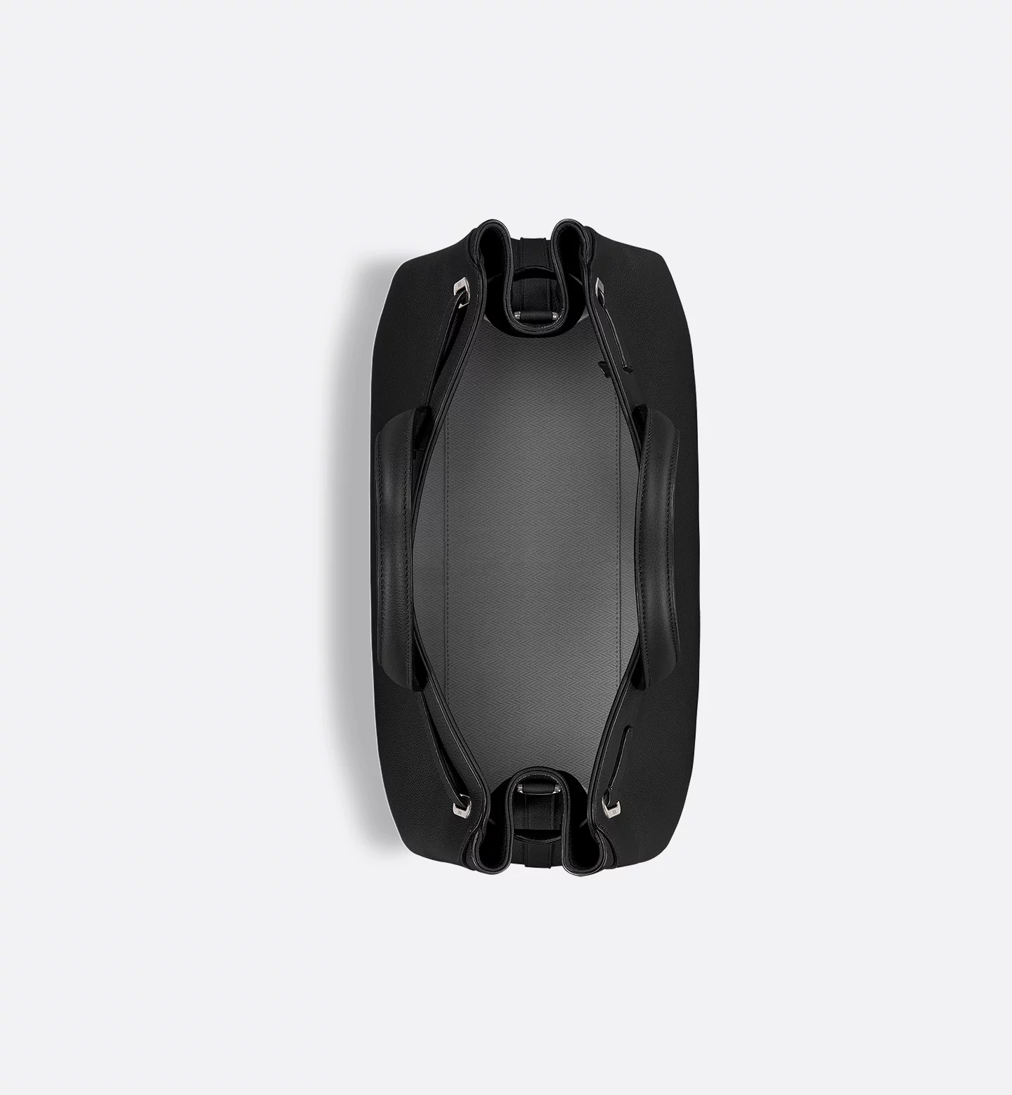 <p>サイドのグラフィカルな構造、Diorシグネチャー入りの底鋲、クッション入りのトップハンドルなど、精緻なディテールが特徴。内側にはスリップポケット2つとジップポケット1つを備え、ヘリンボーンモチーフの裏地を施している。</p>